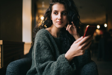 Charming young lady using smartphone at cafe