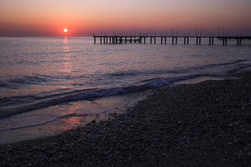 Pier silhouette on the beach at sunrise pink purple orange red skyline and background colors, relaxing holiday concept, in Antalya Turkey.