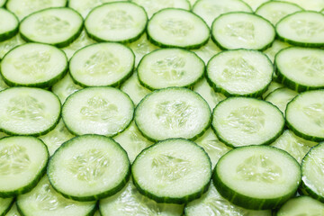 Fresh green slices of cucumber as background.