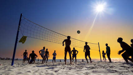 Young multi ethnic silhouette people enjoying time together playing beach volleyball - Teenagers...