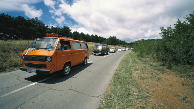 Kocani, Macedonia - 24 Jun, 2018: Volkswagon cars participating in event. Row of vintage German VWs buses and beetles driving on rural road on sunny day