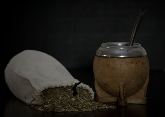 Shot of a brown calabash and a bag filled with mate isolated on a black background