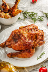 Tasty grilled fried roast chicken Tabaka in a white plate on concrete table with wegetables and spices