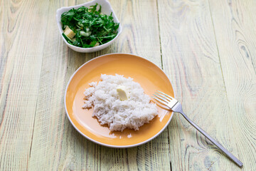White boiled rice and greens salad on a wooden background. Healthy food concept.