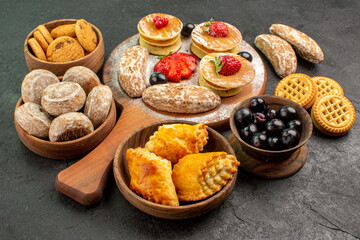 front view tasty pancakes with different sweets on dark background sugar cake dessert