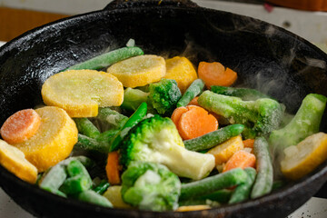 Frozen vegetables in a pan. Mix of different vegetables - carrots, green beans, cauliflower.