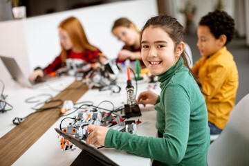 Happy kids programming electric toys and robots at robotics classroom