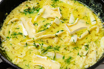 Fried squid in a pan in a creamy sauce with sprouted mustard seeds.