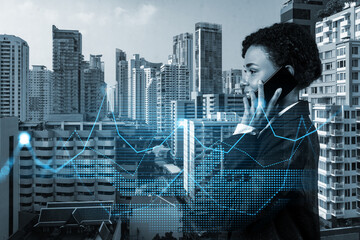 Attractive black businesswoman pensively processing conference call by phone to find financial solution for venture capital project. Hologram chart over Bangkok city background
