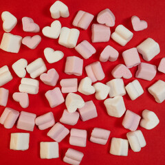 sweets-pink and white marshmallows in the shape of hearts on a red background congratulate you on Valentine's Day.