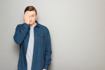 Portrait of anxious man covering half of his face with hand