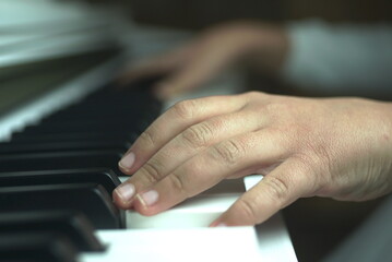 hand of a young girl on the piano keyboard close up