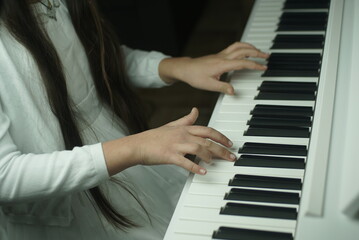 Fototapeta na wymiar hands of a young girl on the piano keyboard