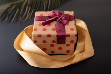 small size red dotted texture gift box with maroon and golden ribbon on black background