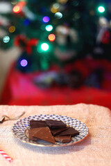 Vintage porcelain plate with chocolate pieces and Christmas decorations. Selective focus.