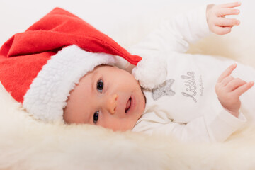 Süßes Baby mit Weihnachtsmütze vor weißem Hintergrund