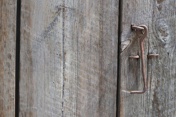 Old wooden door with a metal hook close up.