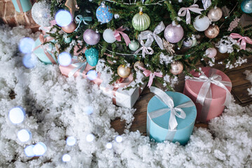 Christmas gifts packed with pink,tiffany paper and tapes under decorated tree. Copy space