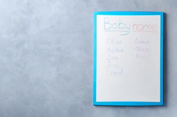 White board with baby names on grey wall. Space for text
