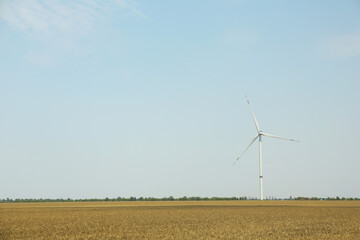 Modern wind turbine in field on sunny day. Energy efficiency