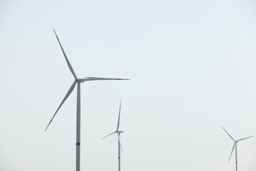 Fototapeta premium Modern wind turbines against blue sky. Energy efficiency