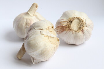 Three heads of garlic on a white plate close-up.