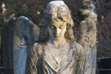 statue of a grieving marble angel covered in patina and snow on the grave