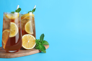 Delicious iced tea with lemon and mint on light blue background. Space for text