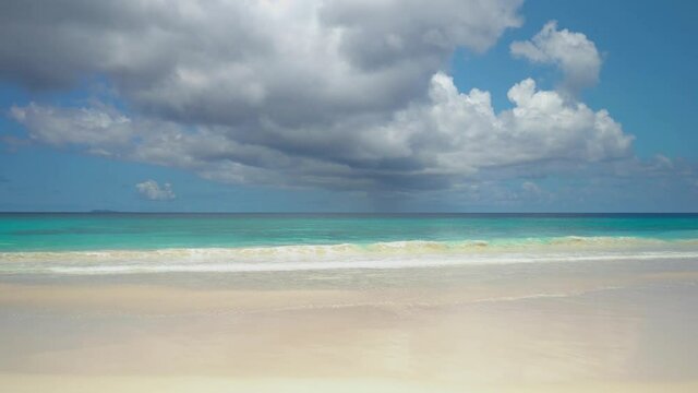 Exotic beach by the ocean with rolling waves on the sandy shore and blue sky