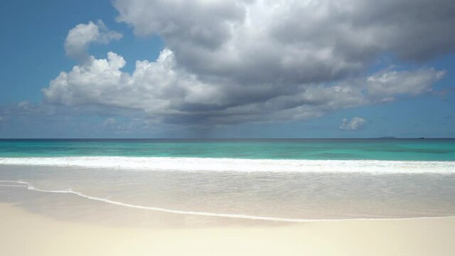 Exotic beach by the ocean with rolling waves on the sandy shore and blue sky