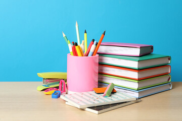 Fototapeta premium Composition with different school stationery on wooden table against light blue background. Back to school