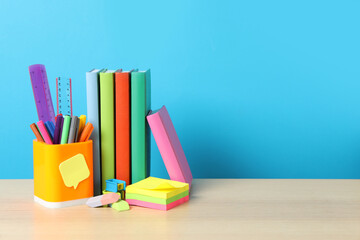 Composition with different school stationery on wooden table against light blue background, space for text. Back to school