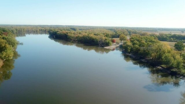 Low angle, slow drone view of the Iowa River and River Trail moving toward a boat ramp and campground on a sunny late summer day; near Hills Iowa