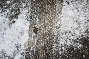 Photo of a trace of a car tire on the snow on the asphalt