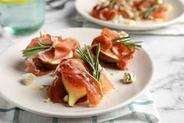 Delicious ripe figs and prosciutto served on white marble table, closeup