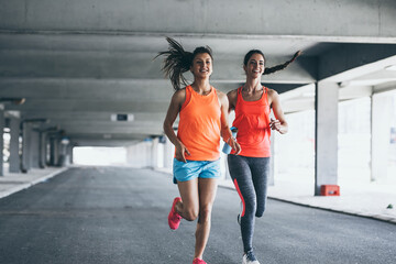 Two female runners jogging around the city .Urban workout concept.	
