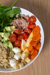 Healthy salad bowl with avocado, tomato, carrot, tuna and quinoa. Vertical isolated image