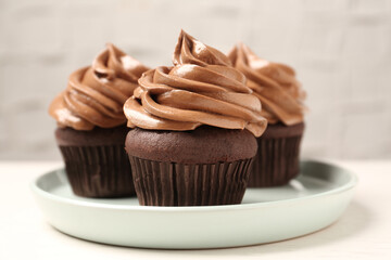 Delicious fresh chocolate cupcakes with cream on white table, closeup