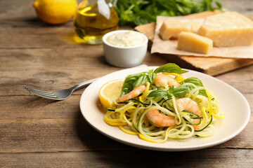 Delicious zucchini pasta with shrimps, lemon and basil on wooden table