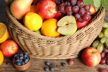 Naklejka na ściany i meble Wicker basket with different fruits and berries on wooden table, closeup