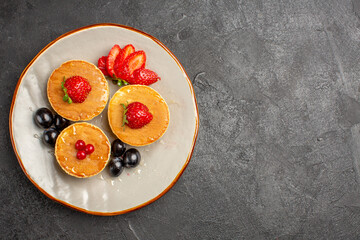 top view yummy pancakes little formed with fruits on the dark background fruit cake pie