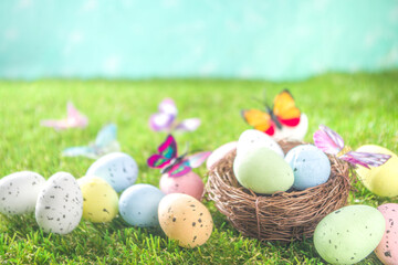 Happy Easter background, spring-time concept. Colorful pastel eggs, nests and bunny toys on  sunny spring day, meadow green grass. Easter greeting card mockup, copy space.