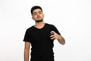 Fototapeta premium Young male model with a perfume bottle in his hand. He is wearing a black shirt. Isolated image and white background.