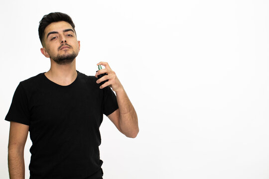 Young male model with a perfume bottle in his hand. He is wearing a black shirt. Isolated image and white background.