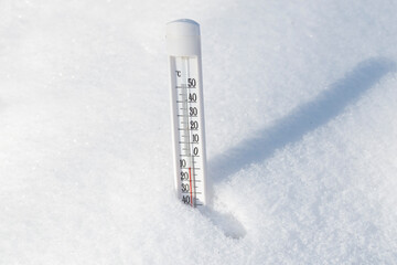 The thermometer stands in a snowdrift and shows a low temperature. The concept of winter