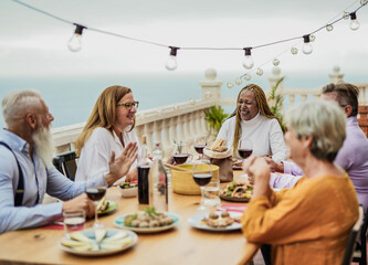 Cheerful multiracial senior friends having fun at a dinner outdoor on patio