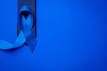 Cancer awareness blue. Blue ribbon, fashion tie isolated on deep blue background. Awareness...