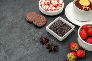 front view yummy tastes with a cup of tea slices of lemon biscuits and fres fruits on black...