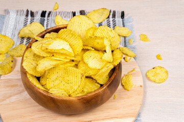 Fluted potato chips on a wooden bowl. Snack, ready meal menu, junk food. copyspace