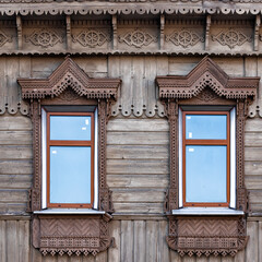 Fototapeta na wymiar Wooden house facade building. Two framed gingerbread trims windows. front view